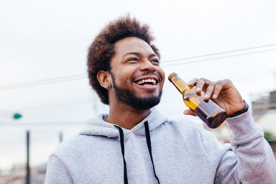 African American Young Male Drinking Beer In Outdoors.