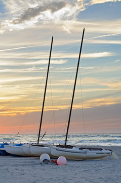 sailboats moored on a tropical beach at sunset