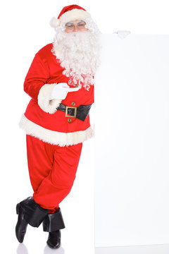 Santa Claus pointing on blank white wall, advertisement banner with copy space. Isolated on white background. Full length portrait