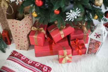 Fototapeta na wymiar Closeup view of many boxes wrapped in red festive wrapping paper. Festive presents under holiday Christmas tree. Horizontal color photography.