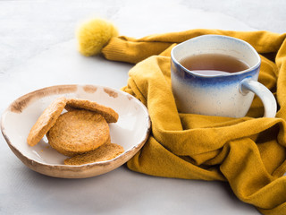 Winter comfort food concept with woman's scarf, mug of tea and cookies. Moment of relax