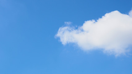 Obraz premium Bright blue clear sky with big white cloud coming from the right, wide screen background