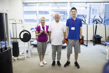 Elderly couple sweating with gym and trainers