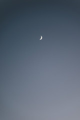 A crescent moon in the blue sky.