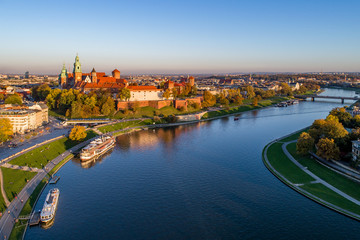 Skyline panorama of Cracow,  Poland, with Royal Wawel Castle, Cathedral, Vistula River, bridge, harbor, ships and onboard restaurant. Aerial view in fall in sunset light. - obrazy, fototapety, plakaty