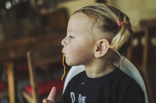 Toddler in pigtails slurping noodles