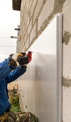 The worker insulates the house from foam plastic