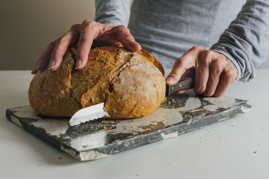 Woman cutting freshly baked bread on marble table