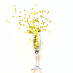 Confetti in the shape of stars poured out glasses of champagne on the white background.