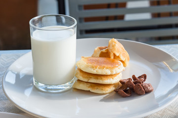 Glass of milk, Pancake and Chocolate cereal on white dish for breakfast.