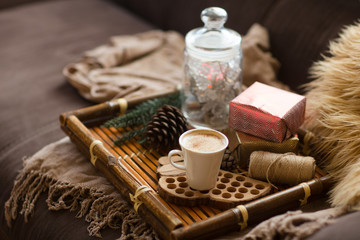 Christmas lifestyle concept.. Cup of coffee on tray, gifts, cones and plaid of living room. Christmas home decoration.