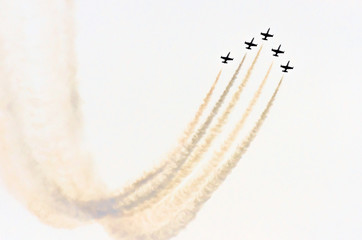 Group of white fighter jet airplane with a trace of white smoke against a blue sky.