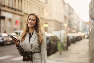 Naklejka na ściany i meble beautiful girl in the street holding a smartphone in her hand