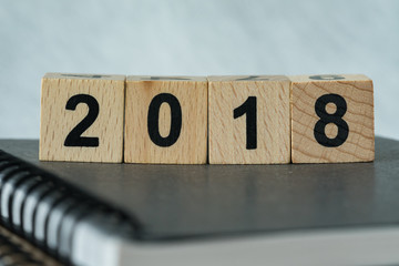 selective focus on wooden cube block with number 2018 on black notebook as new year 2018 aim or goals concept