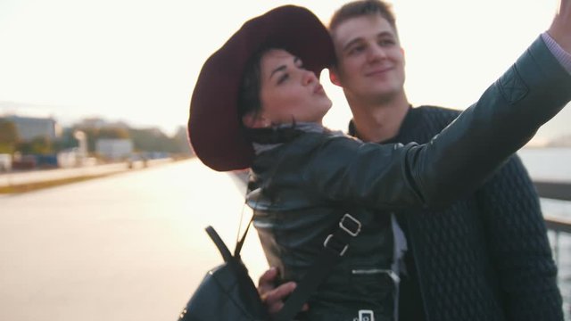 Young man and her wife making selfie at sunset outdoor