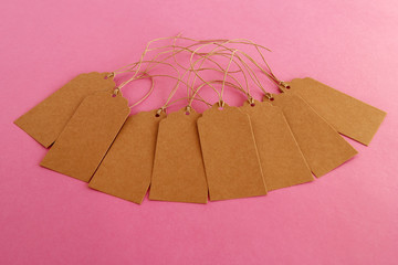 Brown blank paper price tags or labels set on the pink background.