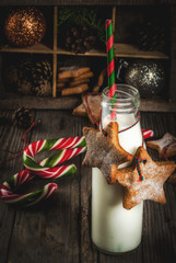 Obraz premium Christmas sweet and treats, Bottles with milk for Santa with gingerbread star cookies with decoration rope and christmas decorations, old wooden background, copy space