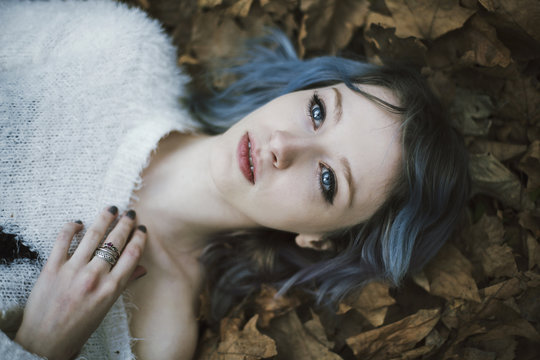 Portrait of a beautiful young woman lying down in autumn leaves