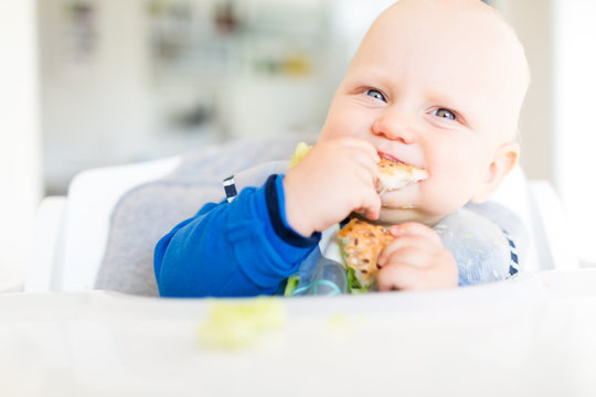 Baby boy eating with BLW method, baby led weaning