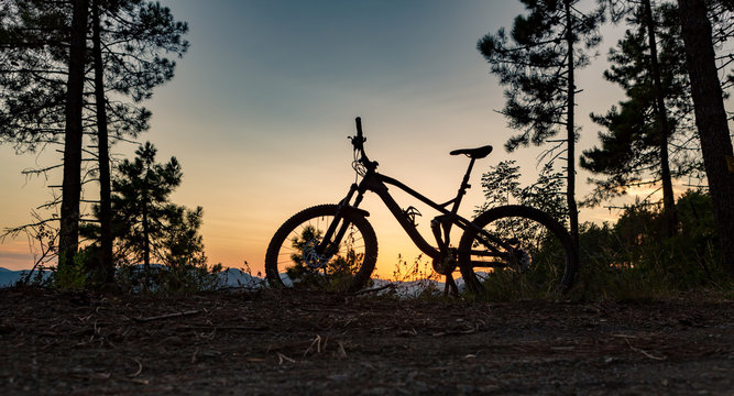 Mountain bike sunset silhouette on forest trail, inspiring landscape