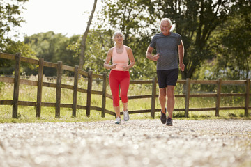 Obraz premium Healthy Senior Couple Enjoying Run Through Countryside Together
