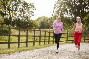 Young And Senior Women Enjoying Run Through Countryside Together