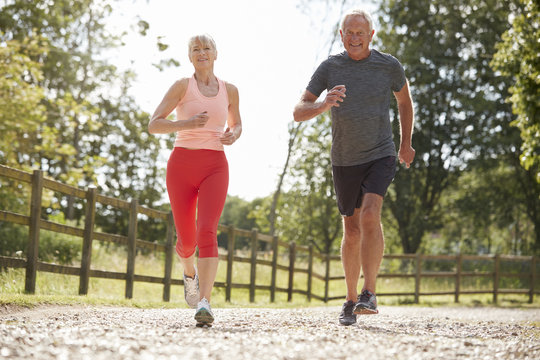 Healthy Senior Couple Enjoying Run Through Countryside Together
