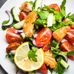 Fresh salad with salmon and vegetables on black background.