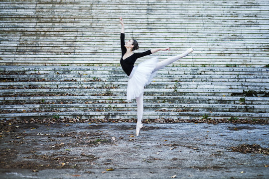 Young beautiful ballerina dancing on the stairways outdoors