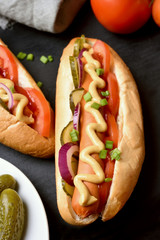 Hot dog with tomato, marinated cucumbers, onion