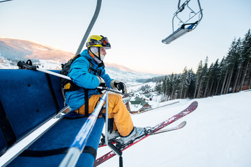 Shot of a skier sitting on a ski lift chair riding up to the top of the mountain copyspace winter...