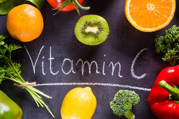 Fruits and vegetables rich in vitamin c with white word inscription by chalk. - obrazy, fototapety, plakaty