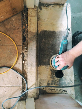 Male carpenter sanding a doorway with an orbital sander.