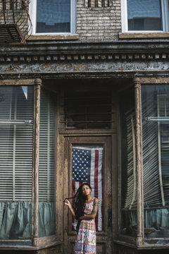 Young woman against old house and USA flag