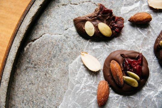 Home made chocolate topped with cranberry, almonds and pumpkin seeds on a stone tray from above