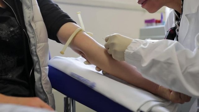 Nurse pricking needle syringe in arm of patient girl drawing blood sample for blood test in blood testing laboratory. Anxious female patient in fear for blood. Stress concept.