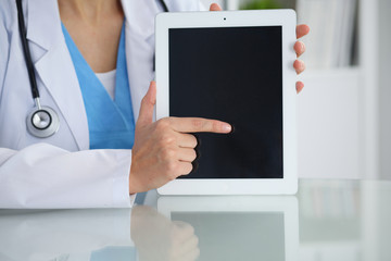 Female doctor pointing into tablet computer, close-up of hands. Physician ready to examine and help patient. Medicine, healthcare and help concept