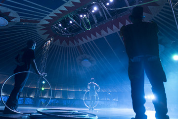 Circus peformer taking a bow with ringmaster and stage hand in foreground