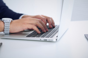 Businessman working by typing on laptop computer. Man's hands on notebook or business person at workplace. Employment  or start-up concept