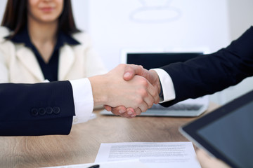 Close up of business people shaking hands at meeting or negotiation in the office. Partners are satisfied because signing contract