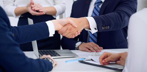 Business handshake at meeting or negotiation in the office, close-up. Partners are satisfied because signing contract or financial papers
