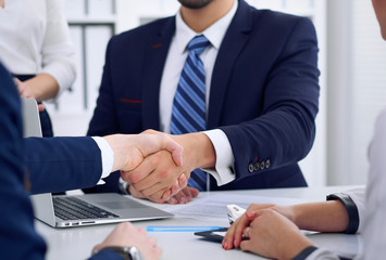 Business handshake at meeting or negotiation in the office, close-up. Partners are satisfied...