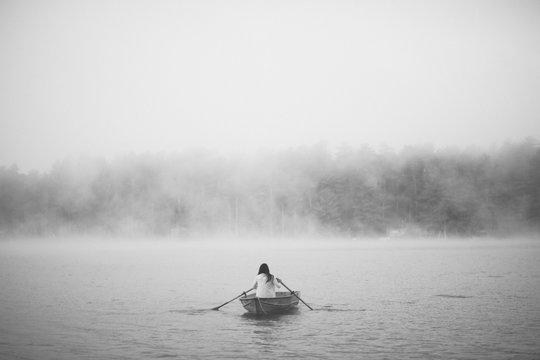 Mysterious woman in row boat on a foggy New England Morning