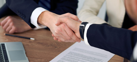 Close up of business people shaking hands at meeting or negotiation in the office. Partners are satisfied because signing contract