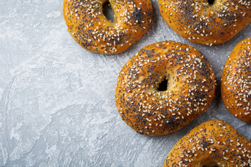 Variety fresh whole-grain bagels with poppy seeds, sesame seeds on a light concrete or stone...