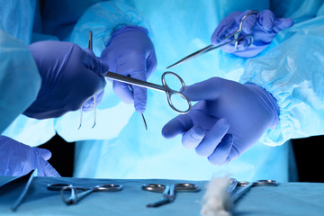 Surgeons hands holding surgical scissors and passing surgical equipment, close-up. Health care and veterinary concept