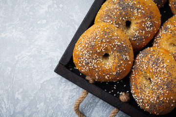 Variety fresh whole-grain bagels with poppy seeds, sesame seeds on a light concrete or stone background. Selective focus. Top view. Copy space.