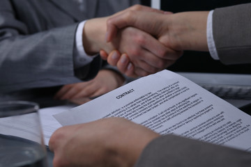 Businesspeople or lawyers shaking hands at meeting. Close-up of human hands at work. Signing contract concept. Low key lighting 