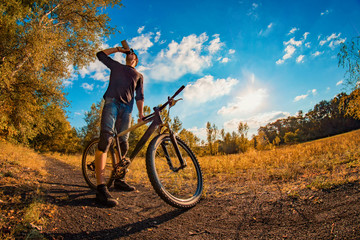 Naklejka premium young man drinks a protein shake from a shaker while taking a bike