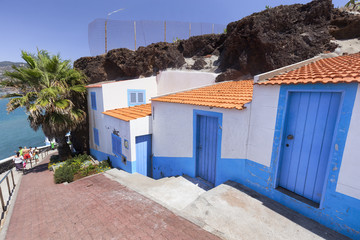 Fototapeta na wymiar Beautiful white and blue houses built around volcanic rock in Sao Martinho in Madeira, Portugal.
